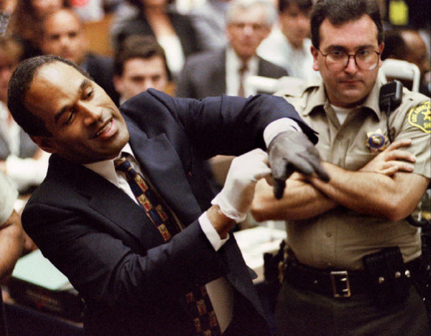 Defendant OJ Simpson wearing one the blood stained gloves found by Los Angeles Police and entered into evidence in Simpson 's murder trial pulls it on his hand in front of the jury at the requestof prosecutor Christopher Darden June 15 Prosecutors sought to prove the gloves fit Simpson's hands